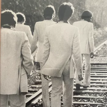 Black and white photo of men walking on train tracks